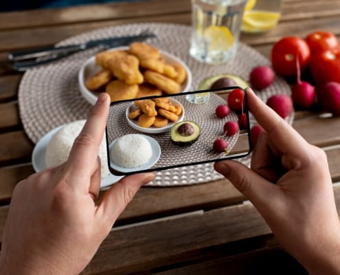 telefono che fa una foto ad un piatto con riso, pomodori e nuggets
