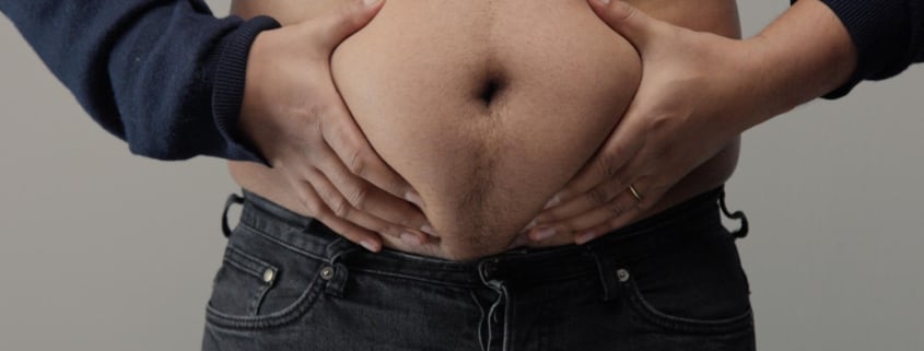 persona con la pancia in vista e la maglietta alzata che si tocca la pancia con le mani